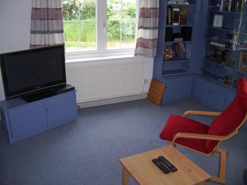a living room with a tv and a chair and a table at Kleines Ferienhaus Im Grünen Bei Lüneburg in Bardowick