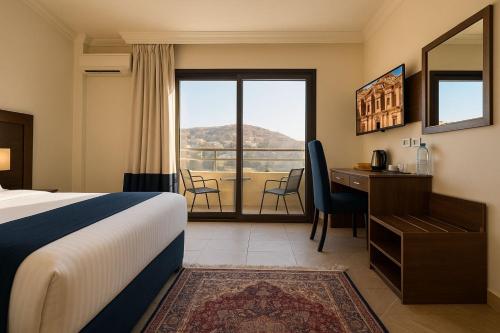 Una habitación de hotel con una cama, un escritorio y una ventana. en Corner View Hotel, en Wadi Musa