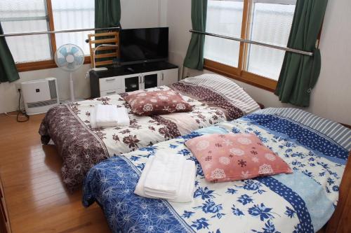 ein Schlafzimmer mit 2 Betten mit Kissen darauf in der Unterkunft MIYUKIHOUSE1番館201 wi-fi babybed wii in Kasugabaru