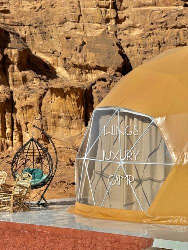 a tent and chairs in front of a rock wall at BUBBlES JOHRH LUXURY CAMP in Wadi Rum