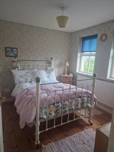 ein Schlafzimmer mit einem Bett mit einer rosa Decke in der Unterkunft Ros Cottage in Carlingford