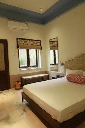 Un dormitorio con una gran cama blanca y dos ventanas. en Kasumal, en Jaipur