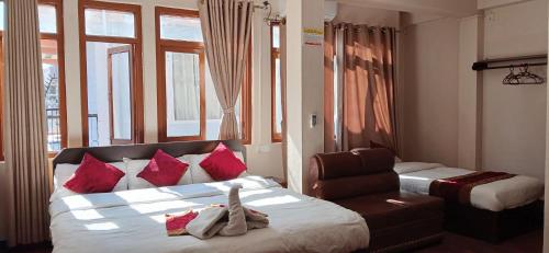 a bedroom with a bed with red pillows and a chair at Hotel Silver Jubilee in Kathmandu