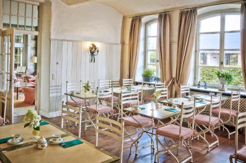 ein Esszimmer mit Tischen, Stühlen und Fenstern in der Unterkunft Der Linslerhof - Hotel, Restaurant, Events & Natur in Überherrn