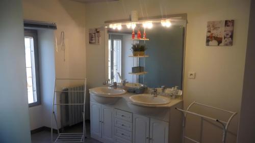 a bathroom with two sinks and a large mirror at Gite les Magnans in Teillet