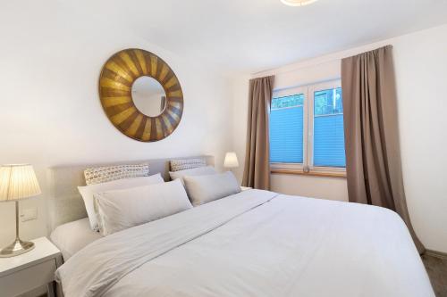 ein Schlafzimmer mit einem weißen Bett und einem Spiegel in der Unterkunft Ferienwohnung Im Laubgarten in Öhningen