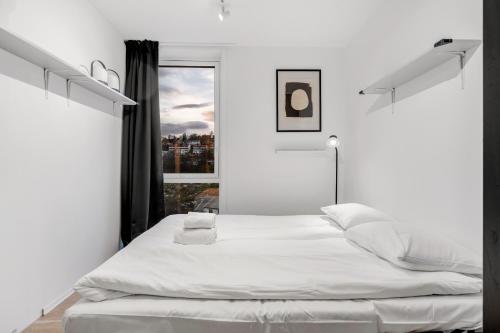 une chambre blanche avec un grand lit et une fenêtre dans l'établissement Modern top apartment in Tromsø, à Hjorten