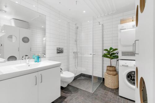 une salle de bain blanche avec un lavabo et une machine à laver dans l'établissement Modern top apartment in Tromsø, à Hjorten