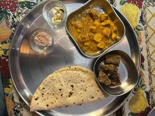 ein Tablett mit Essen, ein Teller mit Brot und Curry in der Unterkunft Ahluwalias Farmstay in Mandlā