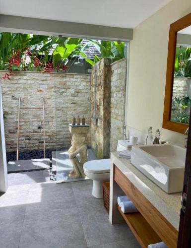a bathroom with a tub and a toilet and a sink at The Chandi Boutique Resort & Spa in Senggigi