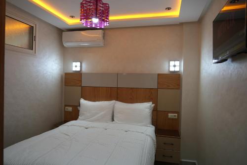 a bedroom with a white bed and a chandelier at APPARTEMENT AMJAD iFRANE in Ifrane