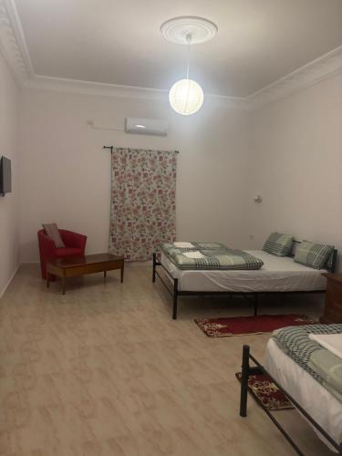a bedroom with two beds and a red chair at Motel EL Golla 