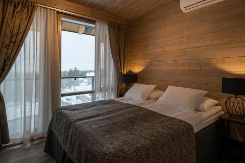 a bedroom with a large bed with a large window at Ski-Inn Kultakero Penthouse in Pelkosenniemi