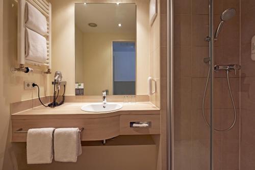 a bathroom with a sink and a shower at H+ Hotel München in Munich