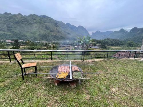 ein Grill mit einem Stuhl neben einem Feld mit Bergen in der Unterkunft Cương Mountain View Homestay in Yên Minh