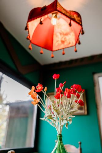 a red lamp and a vase with flowers on a table at Chalet Green in Tbilisi City