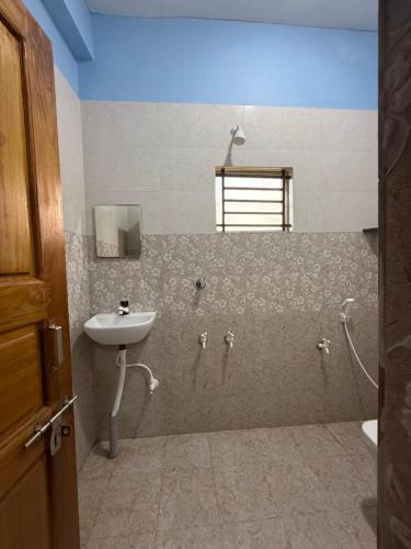 Un baño con lavabo, inodoro y ventana. en Barefoot and Beyond - Crafted with Kenchas, en Gokarna