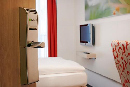 a room with a chair and a tv in a room at H+ Hotel München in Munich