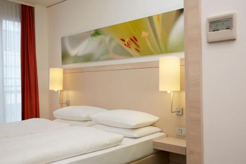 a hotel room with two white pillows on a bed at H+ Hotel München in Munich