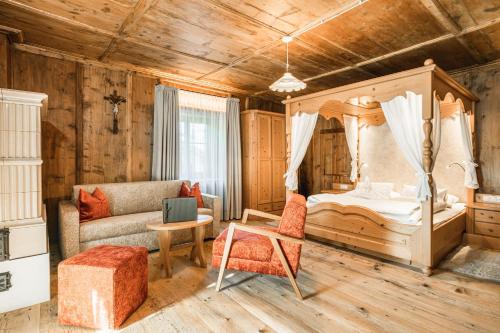 une chambre avec un lit à baldaquin et un canapé dans l'établissement Ansitz Zehentner, à Laion