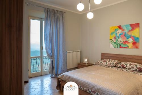 ein Schlafzimmer mit einem Bett und einem großen Fenster in der Unterkunft Belvedere la Rocca in Rocca dʼArce