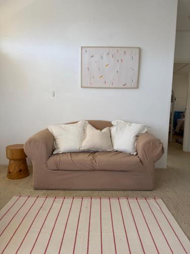 a couch in a living room with a picture on the wall at Marlins Beach Shack Broulee in Broulee
