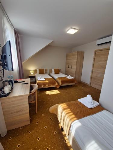 ein Hotelzimmer mit zwei Betten und einem Schreibtisch in der Unterkunft Hotel Avangarda in Różan
