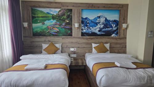 Dos camas en una habitación con un cuadro en la pared. en Prem Durbar Hotel, en Changunarayan