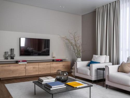 un salon avec une télévision, un canapé et une table dans l'établissement A27 Apartments, à Almaty