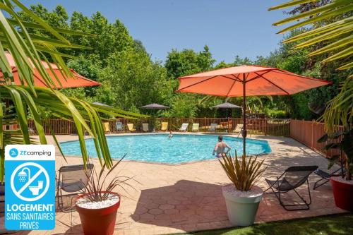 a pool with an umbrella and chairs and a man in the background at Camping 3 étoiles - Parc aquatique - ccba0ec in Urt