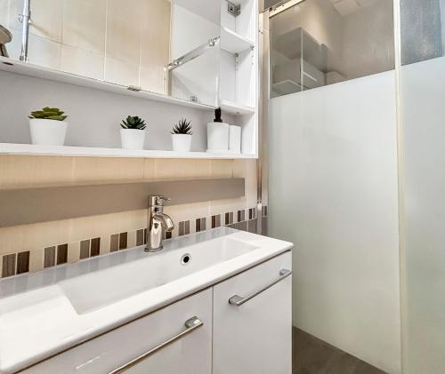 eine weiße Küche mit einem Waschbecken und Regalen in der Unterkunft Chez Alice, Appartement proche de Disneyland Paris in Montry