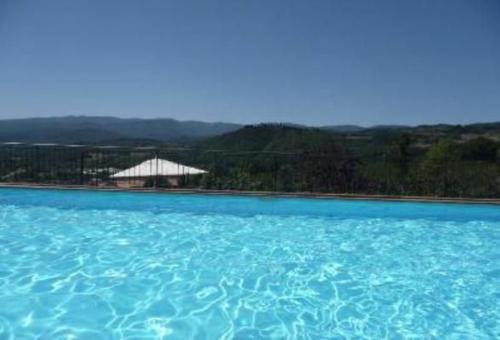 ein großer Pool mit blauem Wasser und einem Gebäude im Hintergrund in der Unterkunft Freistehendes Natursteinhaus für zwei Personen, umgeben von Feldern und Weinreben in Pratovecchio