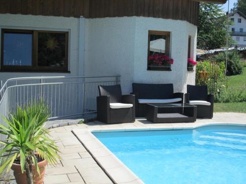 ein Pool mit Stühlen und ein Sofa neben einem Haus in der Unterkunft Ferienwohnung für 2 Personen ca 43 m in Bayerisch Eisenstein, Bayern Bayerischer Wald in Bayerisch Eisenstein