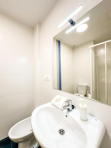a bathroom with a sink and a toilet and a mirror at Apartamento Luzada by ALÔGA in Cee