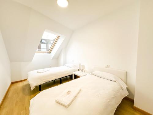 two beds in a small room with a window at Apartamento Luzada by ALÔGA in Cee
