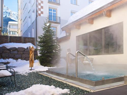 a hot tub in the snow next to a building at Schweizerhof Ferienwohnungen Lenzerheide Haus 6 in Lenzerheide