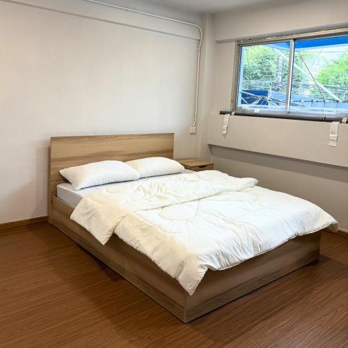 een slaapkamer met een bed met witte lakens en een raam bij Box me in Bangkok