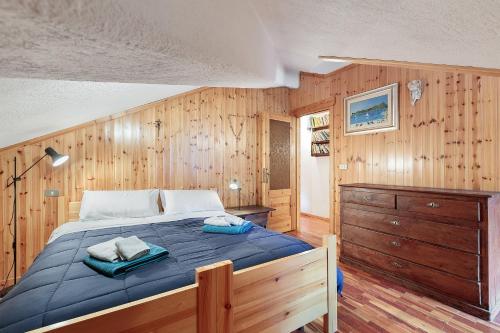 une chambre avec un lit et un mur en bois dans l'établissement Da Gigi e Laura, à Cogne