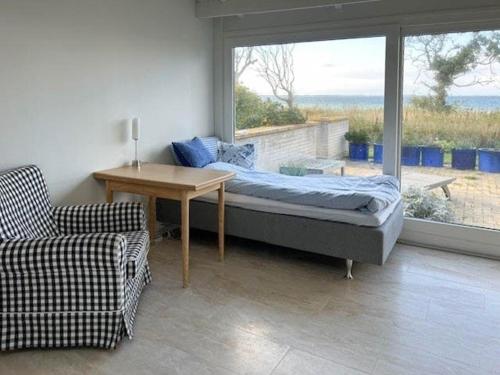 une chambre avec un lit, une table et une fenêtre dans l'établissement Sommerhus Med Sjæl Få Skridt Fra Vandkanten, à Martofte