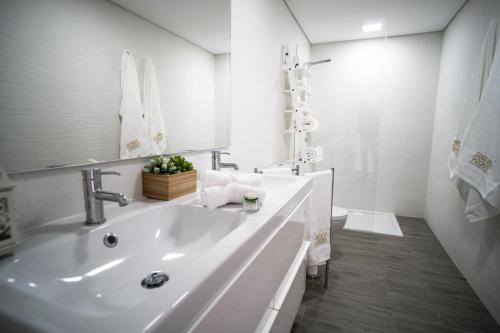 a white bathroom with a sink and a toilet at Islet House in São Roque