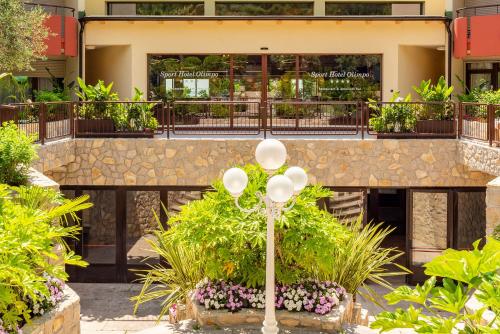ガルダにあるSporthotel Olimpoのたくさんの植物と街灯のある建物