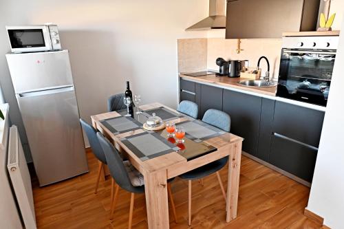 a kitchen with a wooden table with chairs and a refrigerator at Apartman Maela in Županja