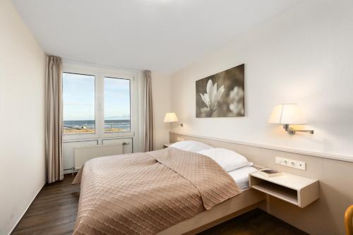 a white bedroom with a bed and a window at Dorfring 36 Seeadler in Stein