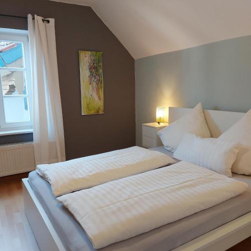 a bedroom with a large white bed with a window at Ferienwohnungen Schneiderhäusl inkl. Chiemgaukarte in Ruhpolding