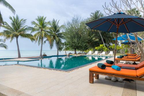 a pool at a resort with an umbrella and lounge chairs at Garto Beach Resort Samui in Ban Bang Po