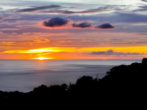 a sunset over the ocean with the sun in the sky at Villa Créole vue exceptionnelle Perle des Hauteurs in Le Carbet