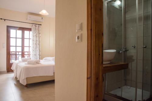 a bedroom with a bed and a glass shower at To Mpalkoni in Chorefto