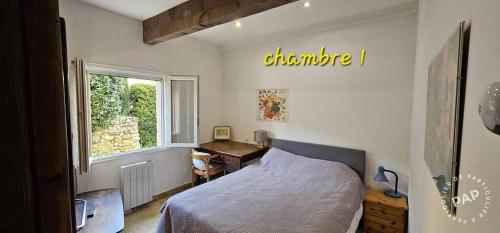 Un dormitorio con una cama y un escritorio y una ventana. en Chez Mich'An Luberon, en Saignon