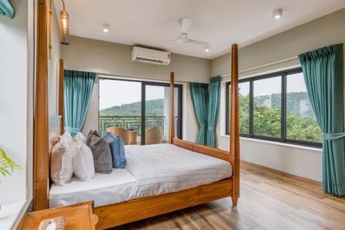 a bedroom with a bed and large windows at SaffronStays Eden Greens in Calangute