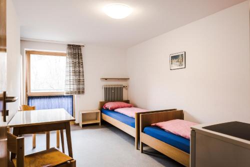 a room with two beds and a table and a desk at Monteurhaus in Hausham